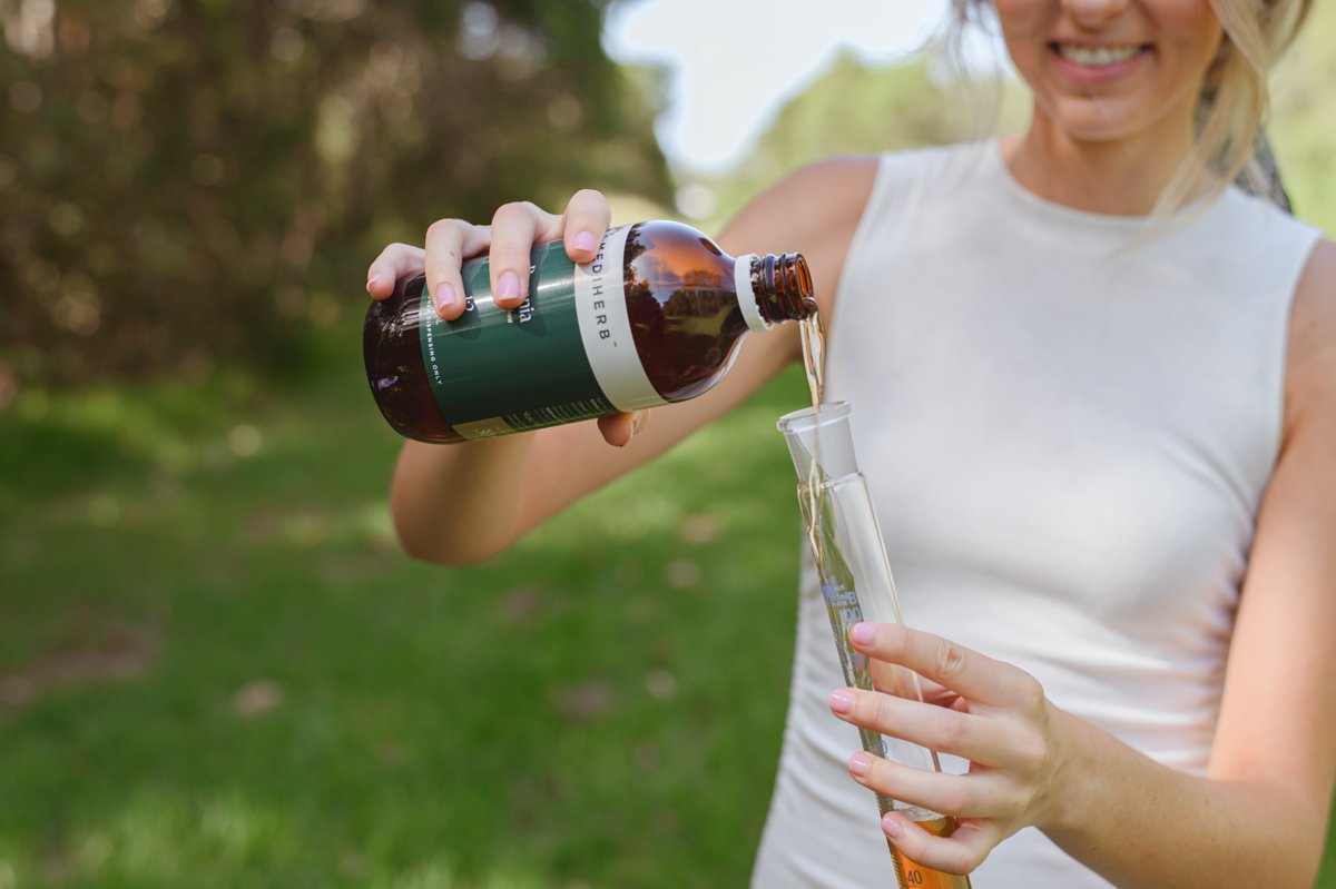Amy Angus naturopath pouring herbal tincture outdoors