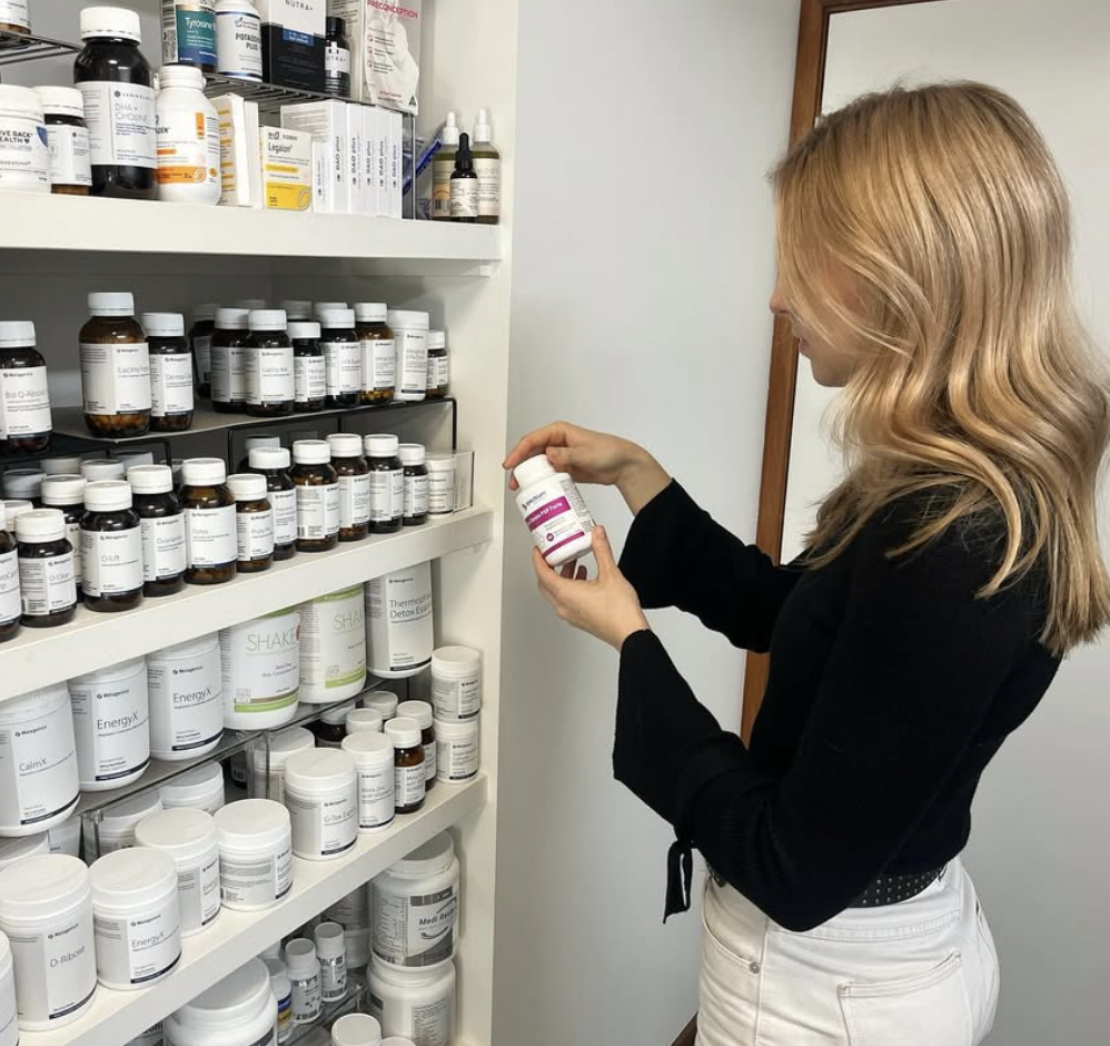 Amy Angus selecting naturopathic supplements from dispensary shelf
